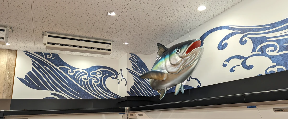 水産売場の壁面に飾られたマグロのオブジェと波の壁画