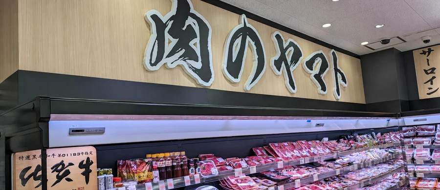 芦屋店の肉のヤマト看板と畜産売場の冷蔵ショーケース