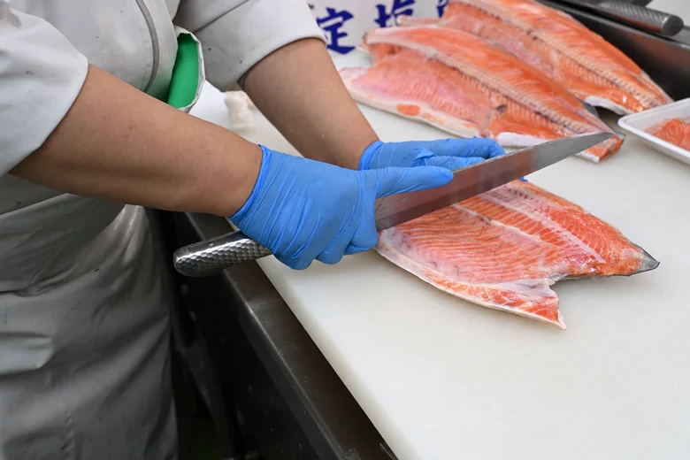包丁を使ってサーモンをさばく水産スタッフの手元