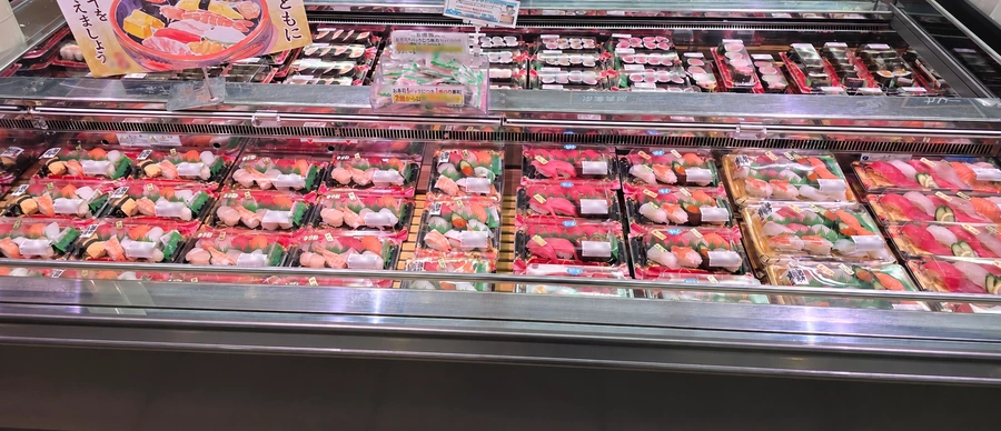 六甲店の寿司売場ショーケースに並ぶ各種にぎり寿司パック